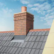 Brick chimney featuring GRP Building Components on a tiled roof, set against a blue sky with scattered white clouds.